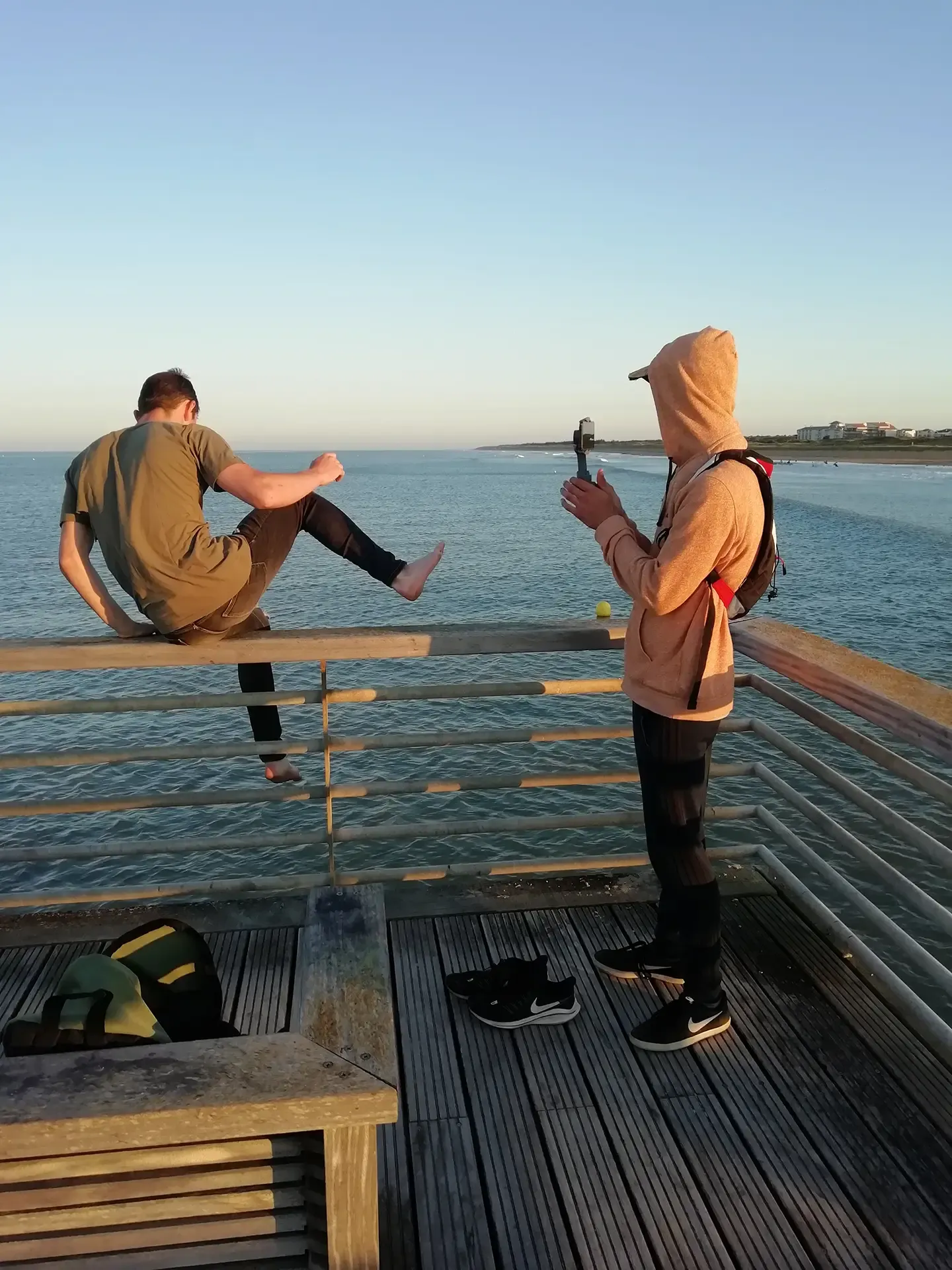 un homme filme un homme assi sur un pont